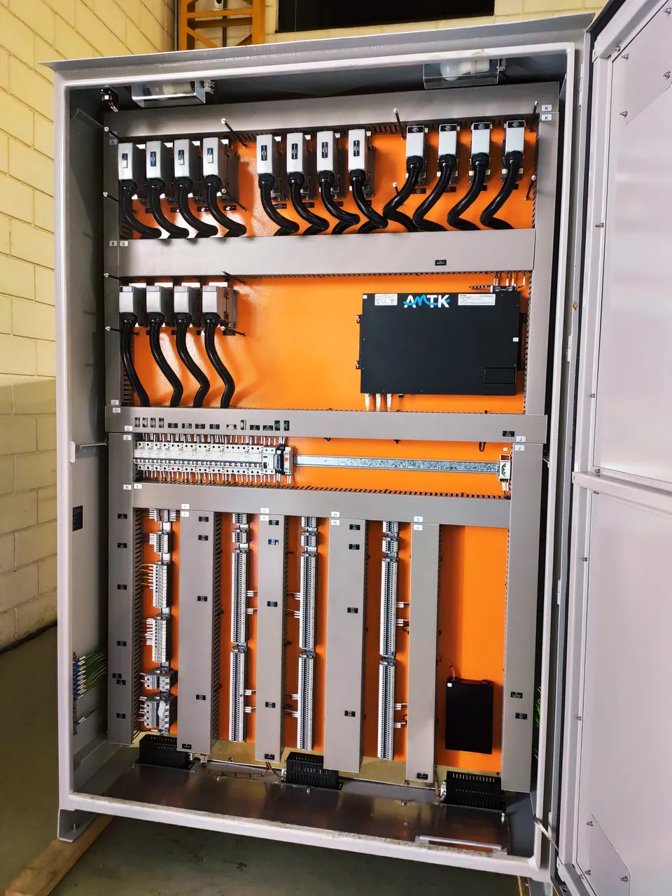 Open transfer cubicle: orange mounting plate with rows of transfer connectors wired with black cables, plus terminal block strips