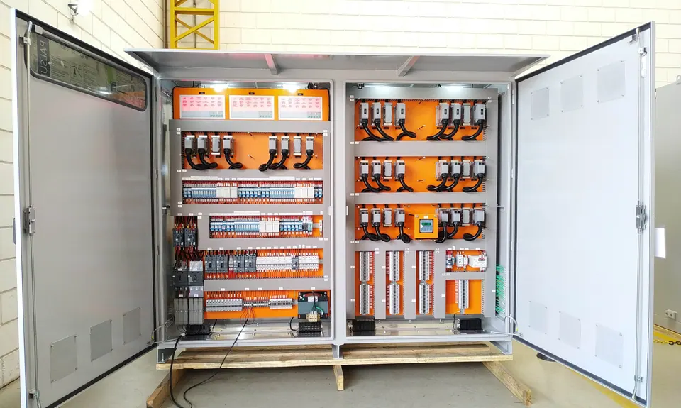 Two-section transfer cubicle with its doors open at the factory: orange mounting plates with transfer connectors, black cables, relays, and terminal blocks