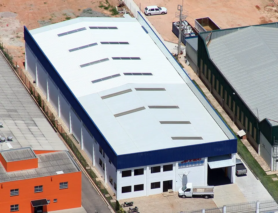 Aerial view of the Alltec Sistemas factory: an industrial building with a light-colored roof, a blue fascia, and the company sign above the entrance