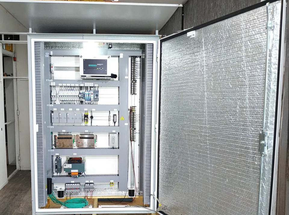 Painel de controle do reator montado, com a porta aberta: monitor no topo, disjuntores, fontes, tomada e transformador