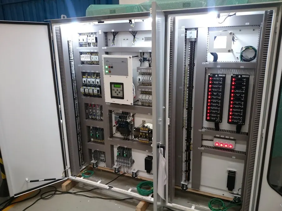 Power transformer control cabinet with both doors open at the factory: relays, circuit breakers, terminal blocks, and an alarm annunciator with red LEDs — end customer Entergy, U.S.